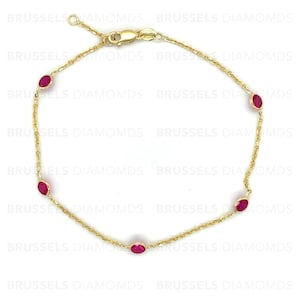 May include: A gold chain bracelet with five red oval-shaped gemstones.