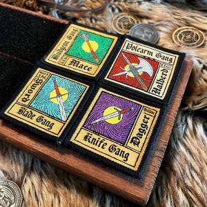 May include: Four black and gold embroidered patches with different weapon types and names. The patches are labeled "Bludgeon Gang", "Mace", "Polearm Gang", "Halberd", "Blade Gang", "Knife Gang", and "Dagger".