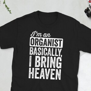 May include: Black t-shirt with white text that reads "I'm an Organist Basically, I Bring Heaven."