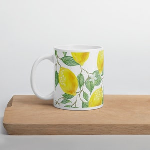 May include: White ceramic mug with a lemon tree design. The mug features yellow lemons, green leaves, and white flowers.