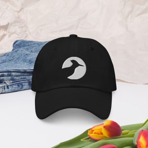 Può includere: Un cappello da baseball nero con un logo ricamato bianco di un uccello in un cerchio.
