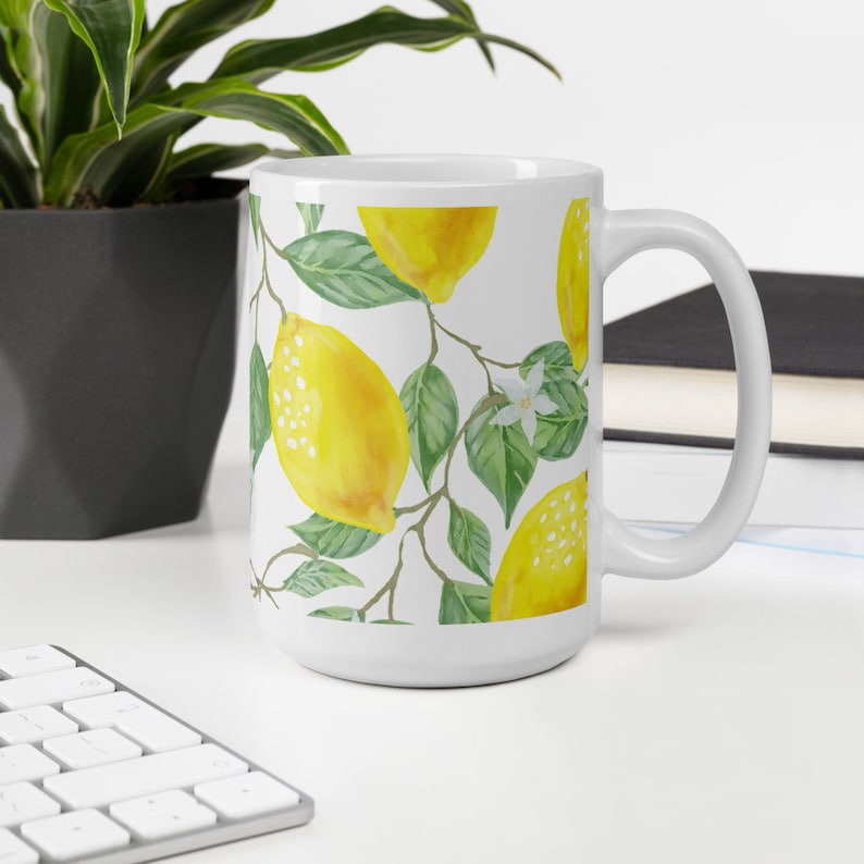 May include: White ceramic mug with a lemon tree design. The mug features yellow lemons, green leaves, and white flowers.