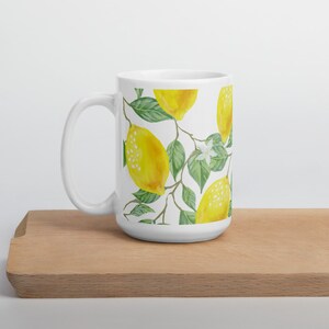 May include: White ceramic mug with a lemon tree design. The mug features yellow lemons, green leaves, and white flowers.