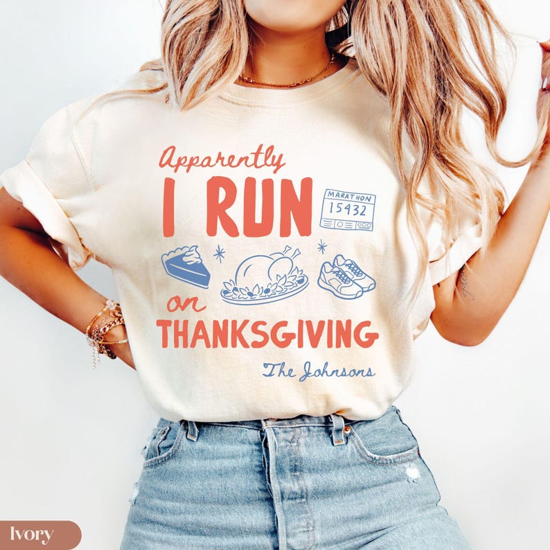 K&ouml;nnte beinhalten: Ein elfenbeinfarbenes T-Shirt mit dem roten Schriftzug Apparently I RUN on THANKSGIVING, blauen Illustrationen eines Tortenst&uuml;cks, eines gebratenen Truthahns, Laufschuhen, einer Marathon-Startnummer 15432 und dem blauen kursiven Text The Johnsons.