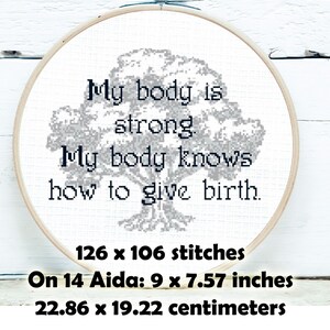 May include: A cross-stitch embroidery in a wooden hoop. The design features a tree and the text "My body is strong. My body knows how to give birth." The piece measures 9 x 7.57 inches and has 126 x 106 stitches.