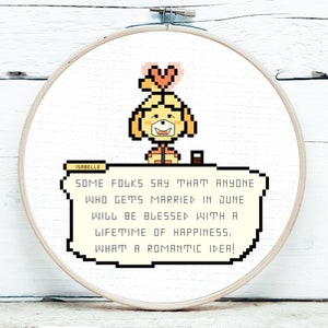 May include: Cross-stitch embroidery in a wooden hoop featuring Isabelle from Animal Crossing. The design includes a pixelated Isabelle character and text that reads, "Some folks say that anyone who gets married in June will be blessed with a lifetime of happiness. What a romantic idea!"