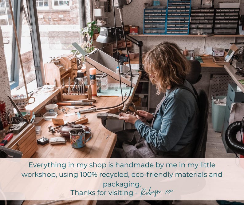 May include: A person working in a well-lit workshop, surrounded by tools and materials. The workspace includes a wooden desk, a window, and various crafting supplies. The text in the image reads: "Everything in my shop is handmade..."