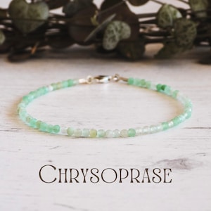 Puede incluir: Un brazalete delicado hecho con cuentas de crisoprasa verde claro y un cierre de plata. El brazalete está sobre una superficie de madera blanca.  CHRYSOPRASE