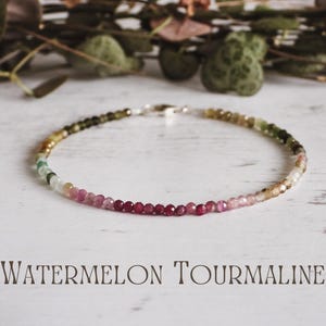 May include: A delicate bracelet made of small, colourful watermelon tourmaline beads. The beads transition from green to pink and red. The bracelet is on a white surface with the words "Watermelon Tourmaline" below.