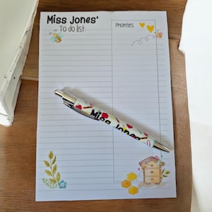 May include: A notepad with the text "Miss Jones' To do list" and "Priorities". A pen with a colourful design rests on the notepad. The notepad features bee and honeycomb illustrations.