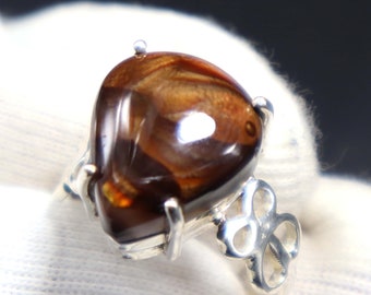 May include: A silver ring with a heart-shaped brown agate gemstone. The ring has a delicate, intricate design.