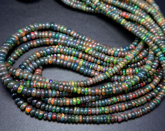 May include: Strands of black opal beads with vibrant flashes of color. The beads are small, round, and strung together, creating a layered effect. The opals display a range of colors, including green, orange, and blue.