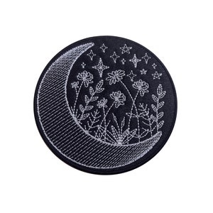 May include: A black embroidered patch featuring a crescent moon and white flowers and stars. The patch is ideal for adding a touch of whimsy to your clothing, bags, or other accessories.