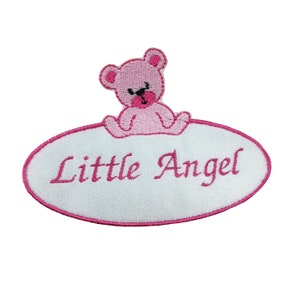 May include: White oval embroidered patch with a pink teddy bear sitting on top and the text "Little Angel" in pink cursive lettering.