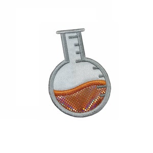 May include: A grey embroidered patch depicting a beaker filled with a brown liquid. The liquid has a glittery, iridescent texture.