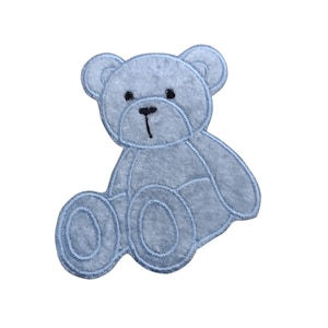 May include: A light blue plush teddy bear applique with black embroidered eyes and nose. The bear is sitting with its legs crossed.
