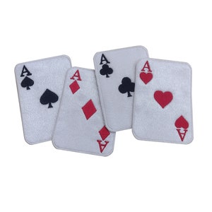 May include: Four white playing cards, each showing the Ace symbol with different suits: spades, diamonds, clubs, and hearts. The suits are embroidered in black and red on the cards.