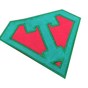 May include: Green and red embroidered patch shaped like a superhero symbol. The symbol is outlined in green and filled in with red.