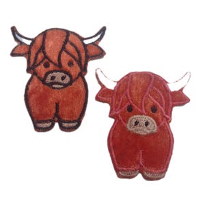 May include: Two embroidered patches featuring a Highland cow design. The patches are in shades of brown and red, with white horns and a detailed face. They are suitable for clothing or accessories.
