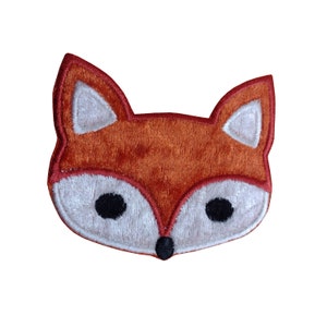 May include: A brown and white embroidered fox face patch. The fox has black eyes and a black nose.