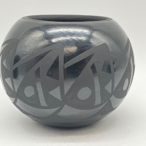 以下が含まれることがあります： 幾何学模様の黒い陶器のボウル。このボウルはネイティブアメリカンの職人によって作られており、伝統的な陶器の美しい例です。