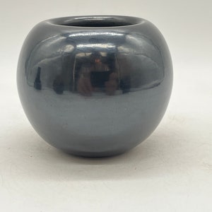 May include: A black, round, ceramic pot with a smooth, glossy finish.
