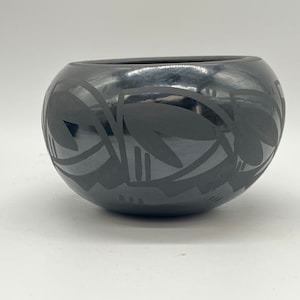 以下が含まれることがあります： 幾何学模様の黒い陶器のボウル。ボウルは黒い粘土でできており、光沢のある仕上げになっています。