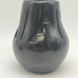 May include: A black ceramic vase with a geometric design. The vase is hand-crafted and has a smooth, glossy finish.