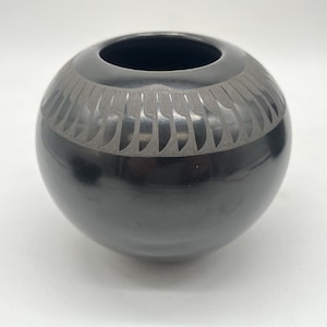 May include: A black pottery bowl with a geometric design around the rim.