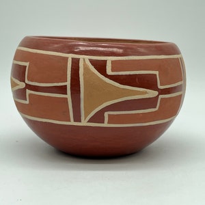 以下が含まれることがあります： オレンジと白の色合いの幾何学模様が施された、小さく丸い赤い陶器のボウルです