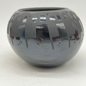 以下が含まれることがあります： 幾何学模様の黒い陶器のボウル。このボウルはネイティブアメリカンの職人によって作られており、伝統的な陶器の美しい例です。