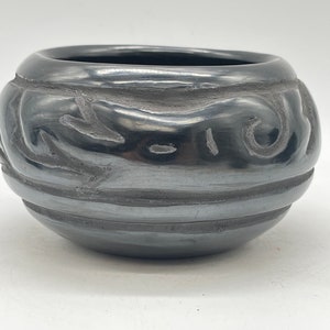 May include: A black ceramic bowl with a swirl design and a shiny finish.