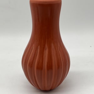 May include: A small, terracotta-coloured vase with a ribbed design. The vase is hand-crafted and has a smooth, glossy finish.