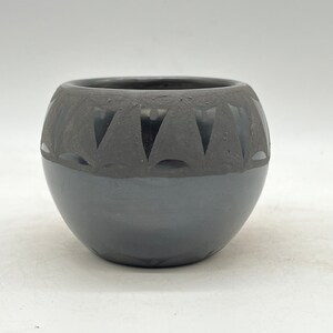 May include: A black ceramic pot with a geometric design around the top edge.