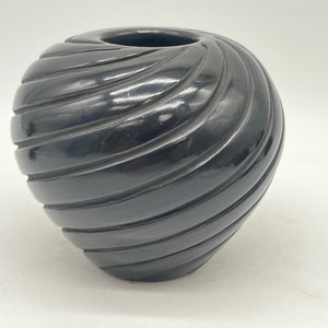 May include: A black ceramic pot with a swirl design. The pot is smooth and shiny.