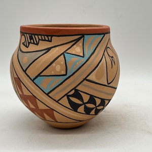 May include: A small, round, tan pottery vase with a geometric design in black, brown, blue, and white.