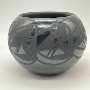 以下が含まれることがあります： 幾何学模様の黒い陶器のボウル。このボウルはネイティブアメリカンの職人によって作られており、伝統的な芸術形式です。