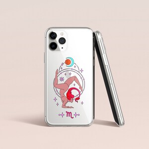 Puede incluir: Una funda transparente para tel&eacute;fono con un dise&ntilde;o de una persona en una postura de yoga con un s&iacute;mbolo zodiacal rosa y morado para Escorpio. La funda tiene una funda de tel&eacute;fono negra y plateada en el lateral.