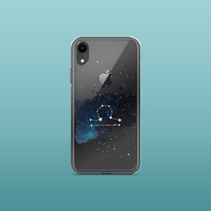 Peut inclure: Coque de t&eacute;l&eacute;phone transparente avec un motif de galaxie noire et un graphique de constellation du zodiaque de la Balance blanche. La coque a une bordure noire et le texte "iPhone" est imprim&eacute; en bas.