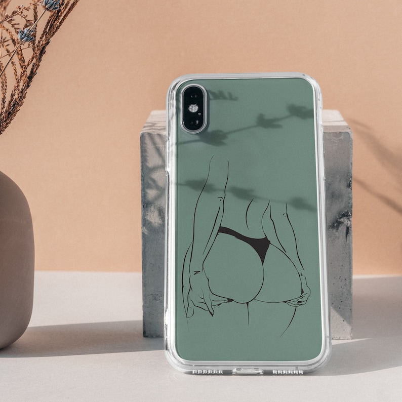 May include: A clear phone case with a green background and a black line drawing of a person's back. The case has a camera lens cutout and a black outline.