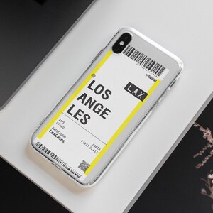 Puede incluir: Una funda transparente para tel&eacute;fono con un dise&ntilde;o de tarjeta de embarque amarillo y blanco. La tarjeta de embarque dice "Los Angeles" y "LAX" con una fecha del 07/20 y el nombre del pasajero "LexCases".
