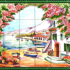 Puede incluir: Un mural de azulejos de cerámica pintados a mano que representa una escena costera mediterránea con un edificio blanco, barcos y vegetación exuberante. El mural de azulejos está enmarcado con un borde verde.