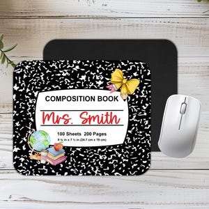 May include: Black and white composition notebook mouse mat with a yellow bow and pencil, a globe, and books. The text reads "COMPOSITION BOOK Mrs. Smith 100 Sheets 200 Pages 9 1/4 in x 7 1/2 in (24.7 cm x 19 cm)"