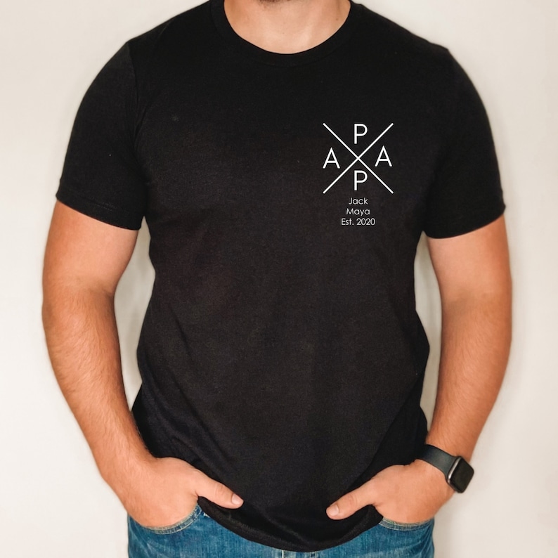 Puede incluir: Camiseta negra con un dise&ntilde;o gr&aacute;fico blanco que presenta las letras "PAPA" en forma de cruz. El texto "Jack Maya Est. 2020" est&aacute; debajo del gr&aacute;fico.