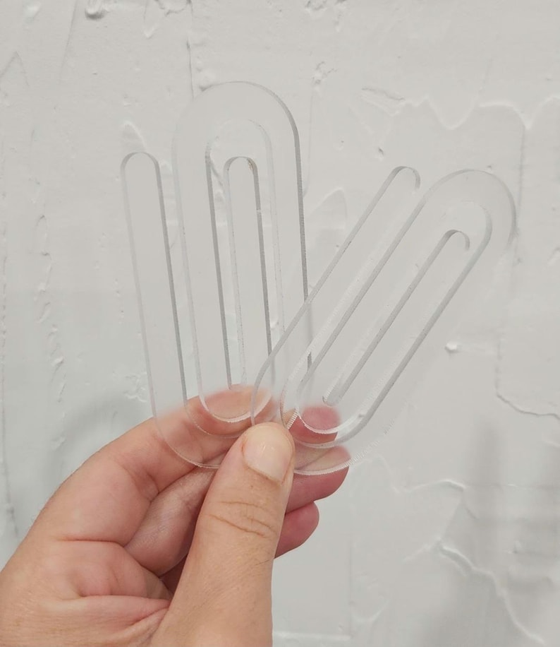 May include: Three clear plastic sewing pattern templates in the shape of an oval with a rounded edge. The templates are stacked on top of each other.