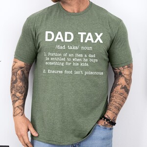 May include: Green t-shirt with white text that reads "DAD TAX /dad taks/ noun 1. Portion of an item a dad is entitled to when he buys something for his kids. 2. Ensures food isn't poisonous"
