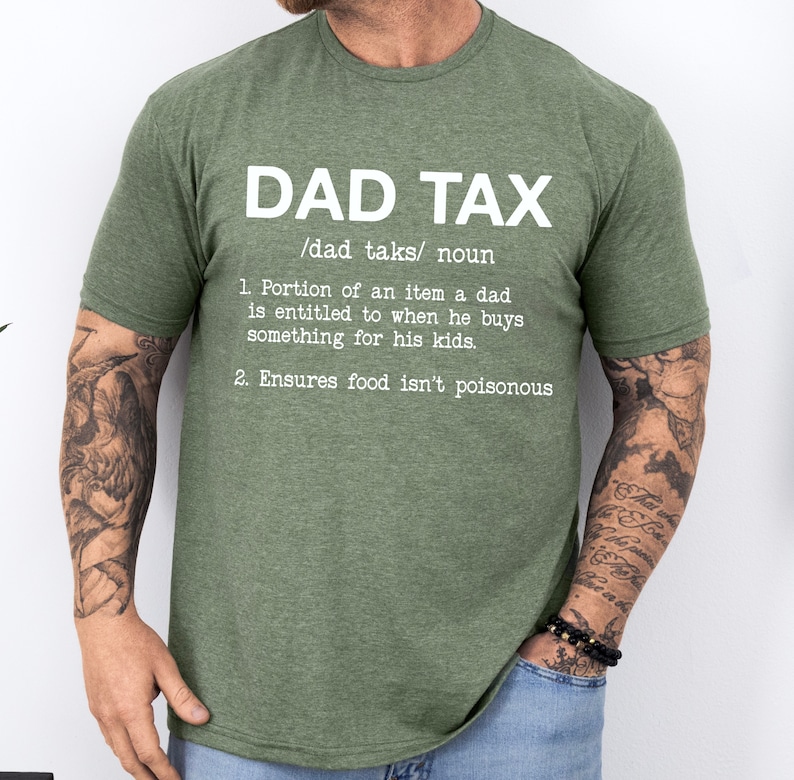 May include: Green t-shirt with white text that reads "DAD TAX /dad taks/ noun 1. Portion of an item a dad is entitled to when he buys something for his kids. 2. Ensures food isn't poisonous"