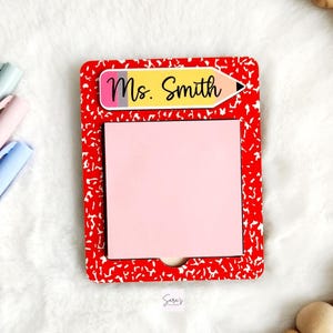 May include: A red and white composition notebook-themed notepad with a pink sticky note section. The notepad features a yellow pencil graphic with the name "Ms. Smith" and a small cutout at the bottom. The notepad is a teacher gift.