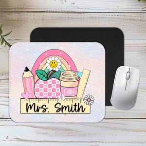 May include: A pink and white mouse mat with a rainbow, apple, pencil, ruler, and coffee cup design. The text "Mrs. Smith" is on the ruler.