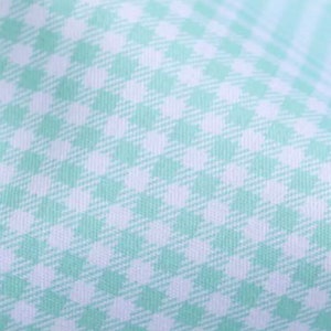 May include: A close-up of a white fabric with a light green gingham pattern.